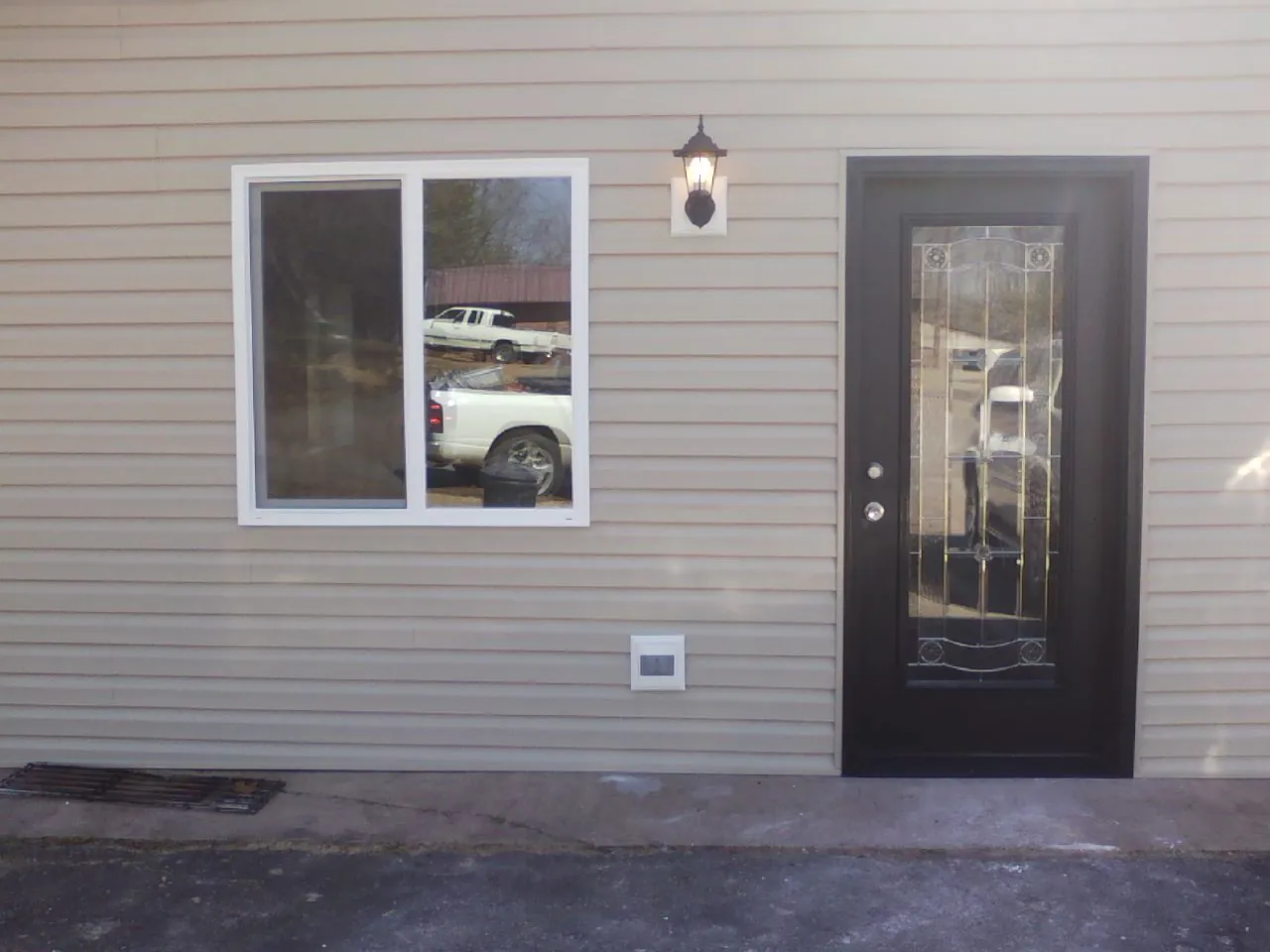New siding, window and entry door on the side of an addition in Lancing