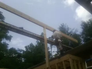 Carpenter setting a ridge beam over a new addition frame — Ice Dam Removal by Roofing Brothers in Lancing