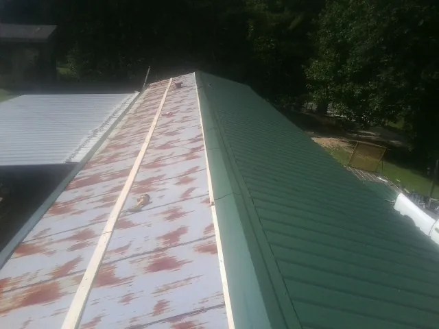 Old rusted panels beside newly installed green metal roofing — Wind Damage Roof Repair by Roofing Brothers in Lancing