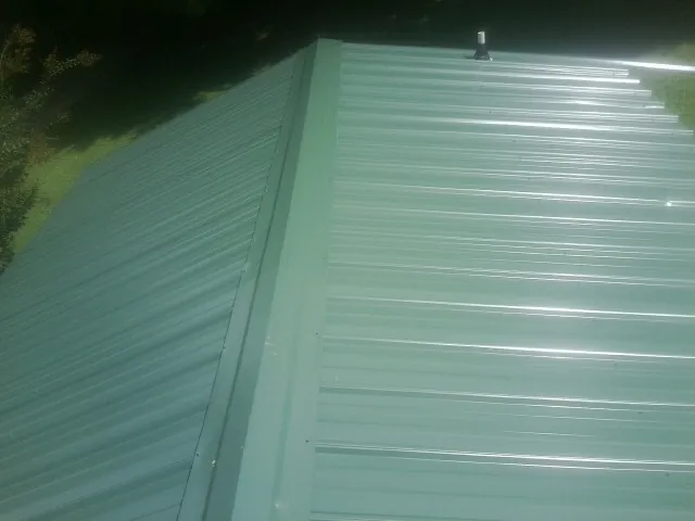 New green metal panels meeting at the ridge of a roof — Flat Roof Repair work by our crew in Lancing