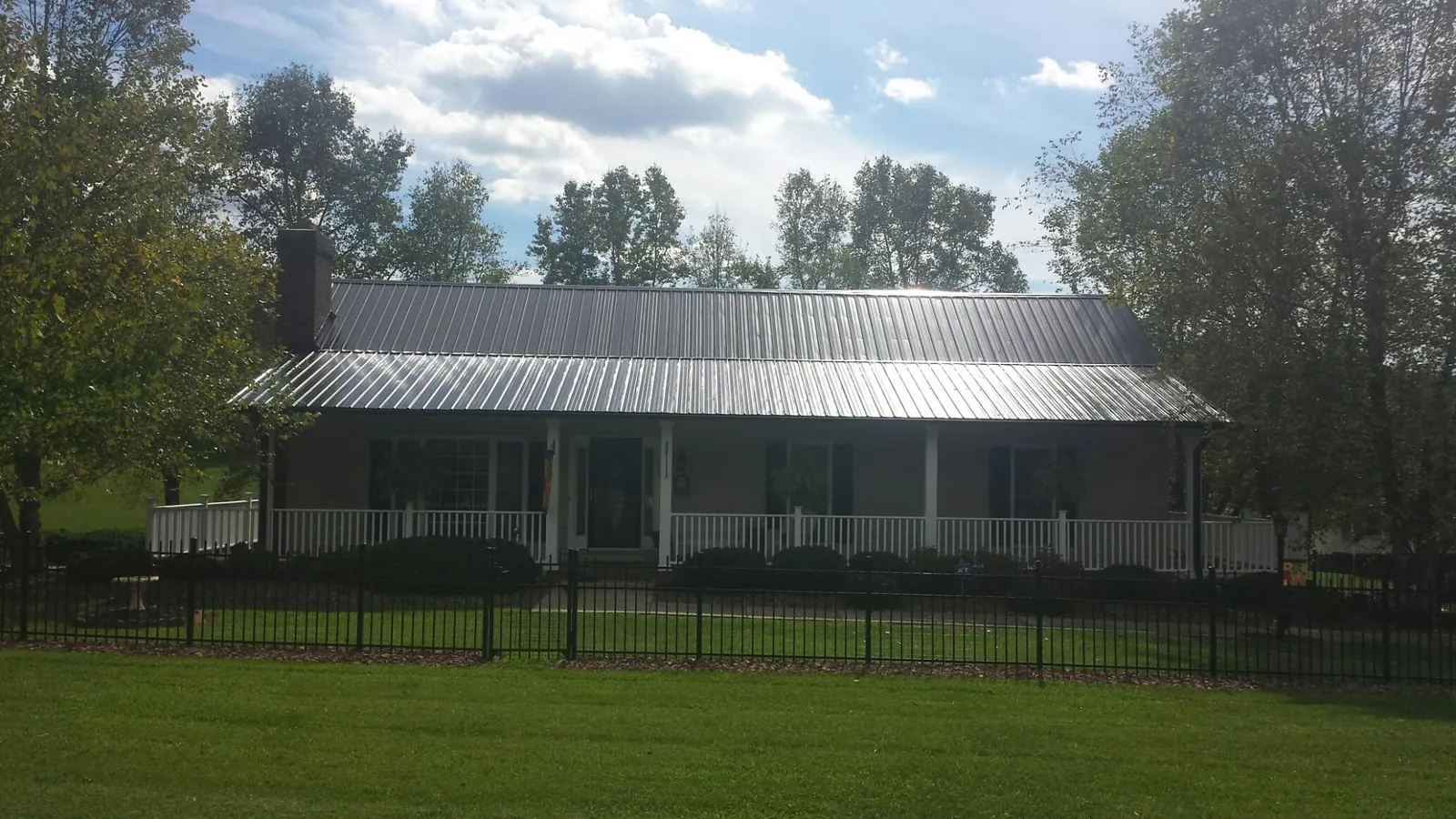 Gray metal roof on a brick ranch with a full width front porch — Gutter Guard Installation work by our crew in Lancing