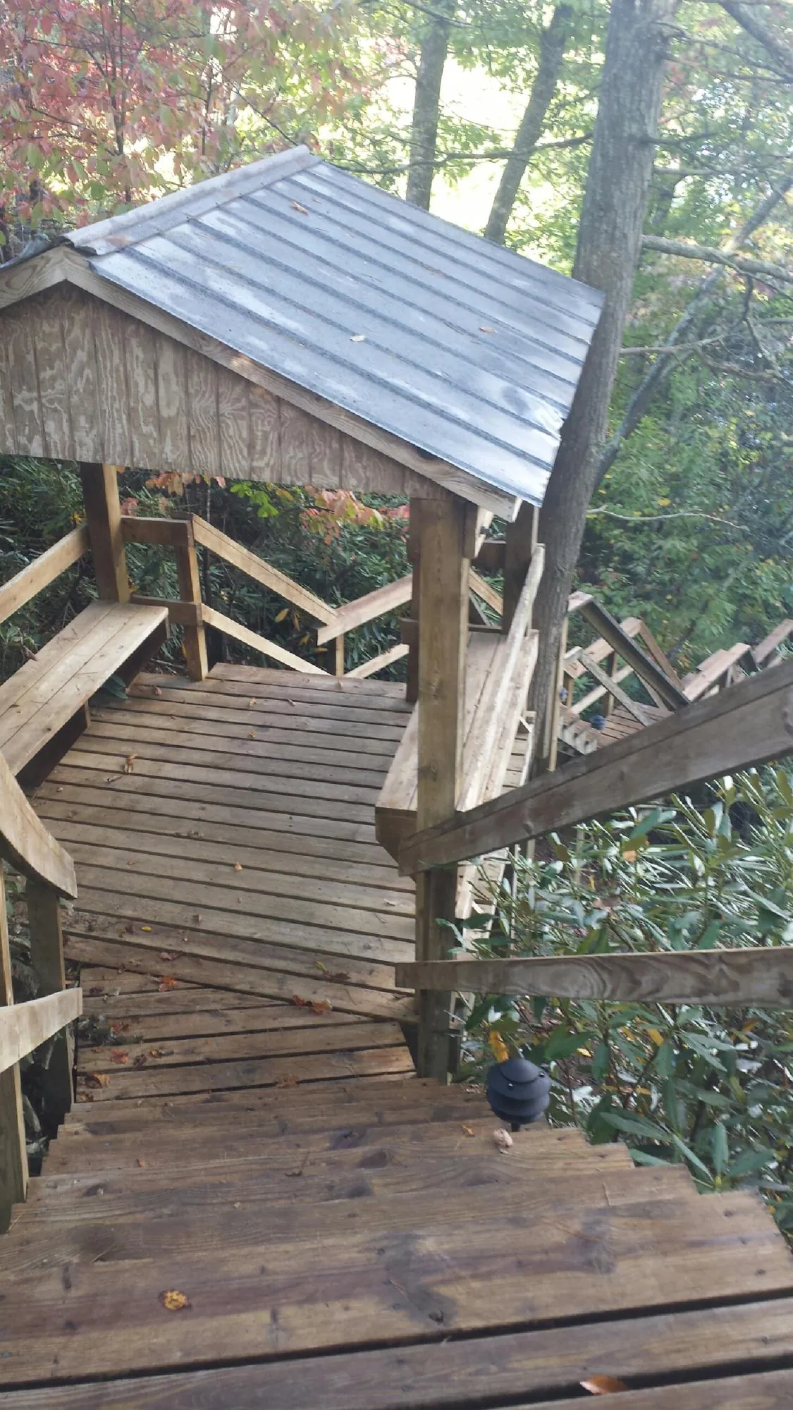 Metal roofed shelter over wooden steps on a wooded walkway — Skylight Repair & Installation work by our crew in Lancing